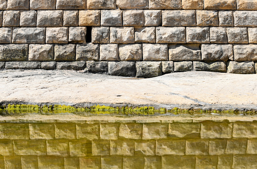 Stone wall is reflected in the water