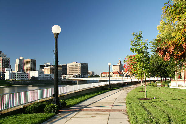 Morning Stroll In The Park 1 Skyline Morning Stroll In The Park. Riverscape sidewalk inviting excercise. Dayton, Ohio. Note the near lamp globe is dirty at 100%. dayton ohio skyline stock pictures, royalty-free photos & images