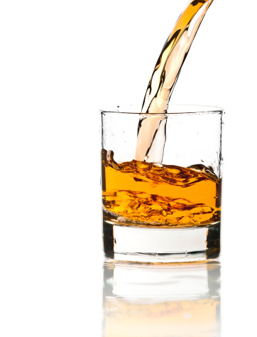 Pouring whiskey in a clear glass, on white background