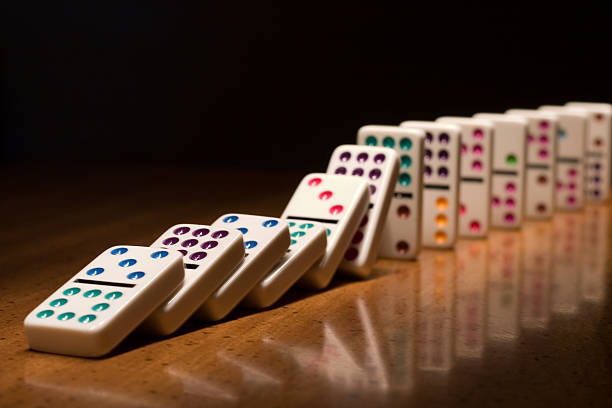 A lined up set of dominoes falling on top of one another Falling dominoes on table. domino photos stock pictures, royalty-free photos & images