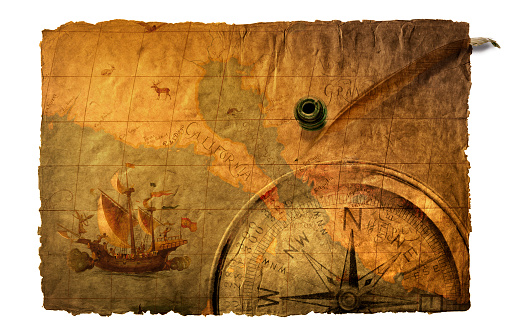 Compass, quill, and old world map on richly textured surface