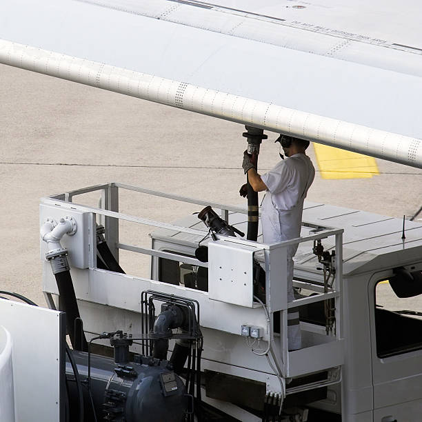 Airport worker refuelling an aeroplane before take off stock photo