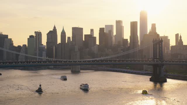 New York City Skyline at Sunset. Aerial Footage from a Helicopter. Modern Skyscraper Buildings Shot Near Manhattan Bridge. Busy Metropolis with Transportation Both on Roads and Water