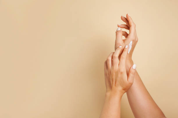 beautiful young woman hands with cosmetic cream. woman applies cream on her hands on beige background, copy space - 潤手霜 個照片及圖片檔