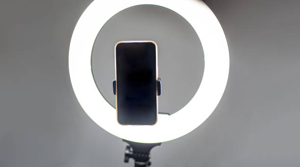 istock Selfie LED ring light with smartphone. Blogging equipment. Studio background. 1571670140