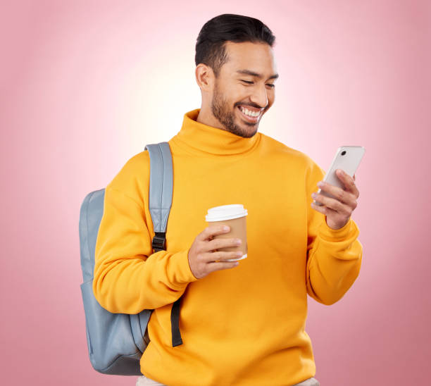 istock Backpack, phone and student or man on studio pink background for scholarship, university or college results. Learning, education and happy person in bag, coffee break and study information on mobile 1571670145