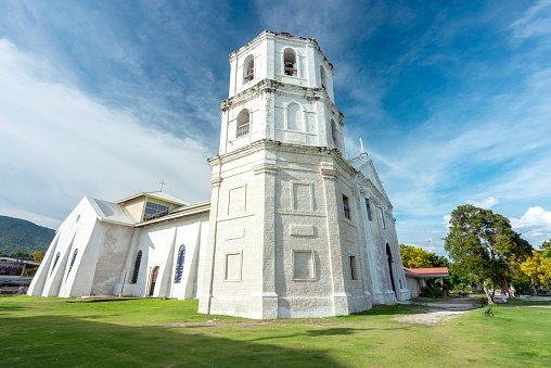 Exterior view of the holy Catholic edifis,showing it's prominent bell tower,facing south-east,next to the Parish Convent of Oslob and Cuartel ruins.Softly lit,surrounded by a neat green grass lawn.