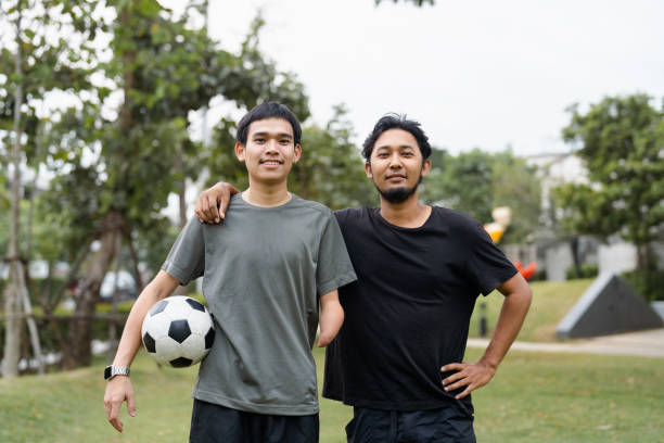 istock Handicapped man with friend exercise at a public park. 1571680409