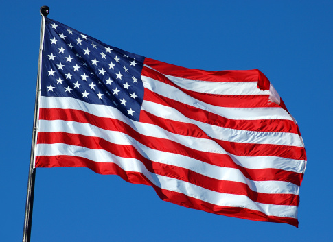 United States flag waving on a blue sky with white fluffy clouds