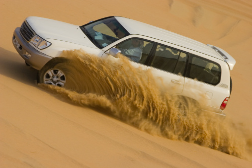 Drifting off road car 4x4 in desert. Freeze motion of exploding sand powder into the air. Action and leasure activity.