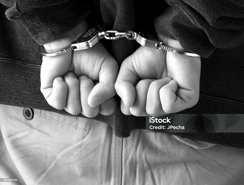 Primo piano maschi clenched pugni Handcuffed dietro la schiena - Foto stock royalty-free di Manette