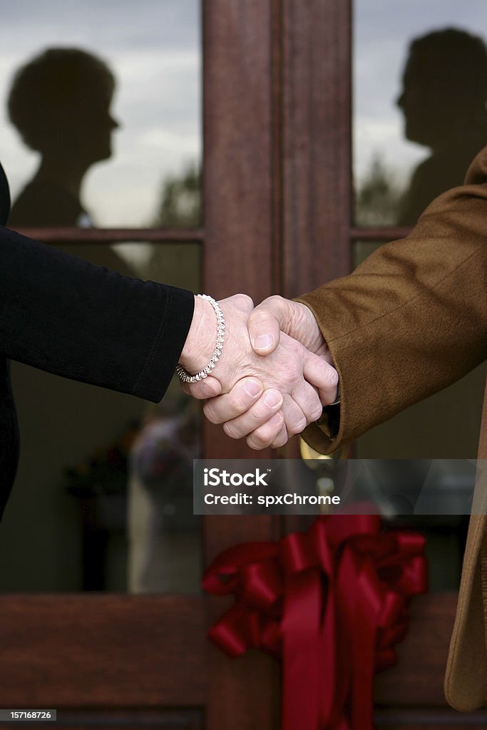 Grand Opening - Handshake Shaking hands at the grand opening of a new building.  Ribbon/Bow on front door. Financial Occupation Stock Photo