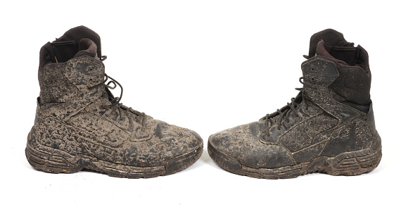 Black shoes, covered in mud, isolated on white