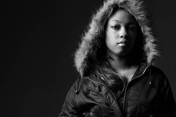 scared girl in hood looking at camera on black background with copy space