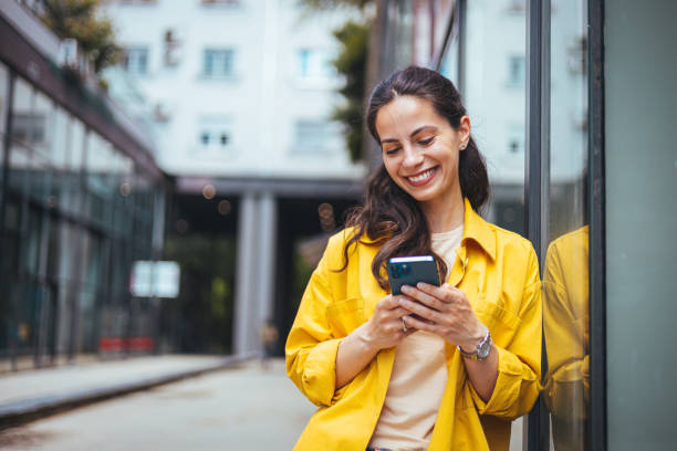 femme professionnelle des affaires marchant dehors et envoyant des sms depuis son téléphone portable. - jubilee photos et images de collection