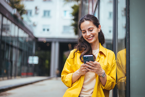 Shot of a beautiful mature businesswoman texting. Mature businesswoman walking outdoors and using cellphone. Female business professional walking outside and texting from her mobile phone.