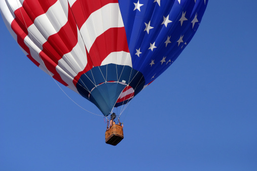 A stunning shot of a patriotic hot air balloon with stars and stripes design against a blue sky.