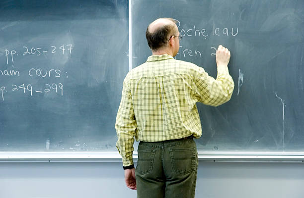 Image of a teacher writing on a chalk board.