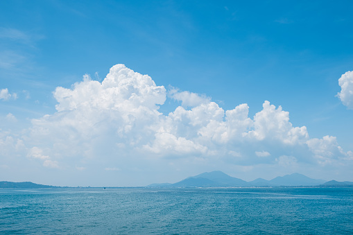 White cloud and blue sky over the ocean . Island view from the sea . Summer tropical landscape .