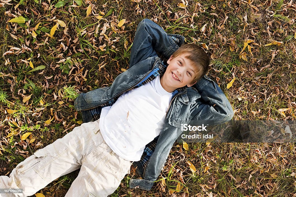 Ritratto di ragazzo Sdraiato su un erba - Foto stock royalty-free di Ambientazione esterna