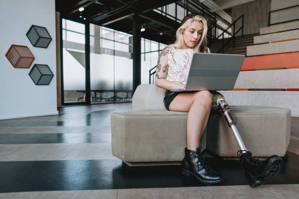 Woman with prosthetic leg working on laptop