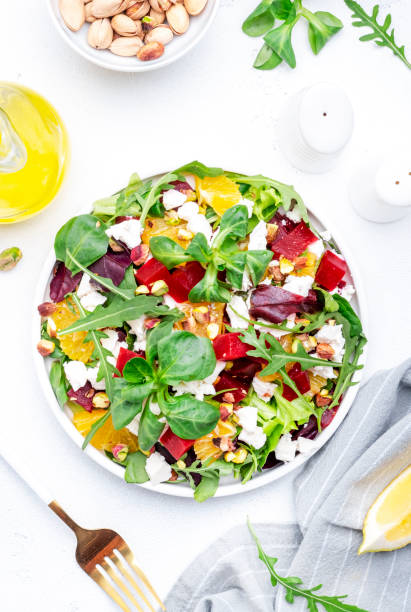 istock Beetroot and white cheese salad with arugula, lettuce,  orange and pistachios on white table. Fresh useful dish for healthy eating 1571722241