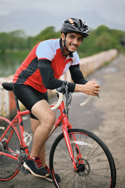 istock Active cyclist wearing protective gear, beaming with joy as he poses with his bicycle for the camera. 1571724489