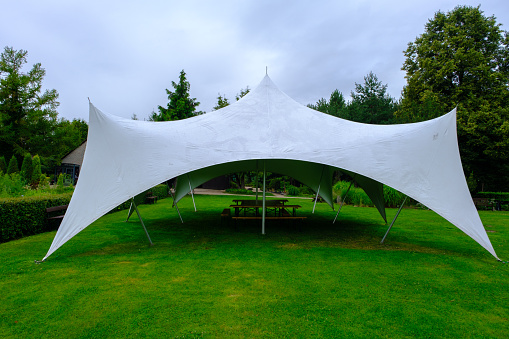 white tarpaulin stretched, shaded from sun and rain. For holding various events in the garden