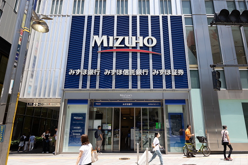 Tokyo, Japan - July 2, 2023 : Pedestrians walk past the Mizuho Bank branch in Tokyo, Japan. Mizuho Bank is a leading global bank with one of the largest customer bases in Japan.