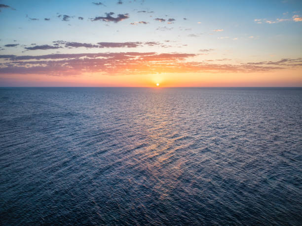 Aerial view of the sun rising over the mediterranean sea, with coloured clouds
