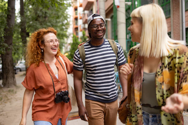 istock Cheerful friends talking during a spring walk on the street. 1571775428