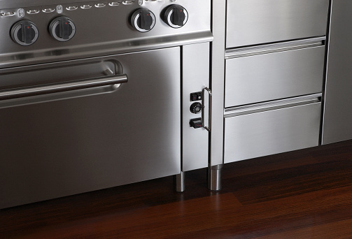 Close-up of professional stove on hard-wooden floor in contemporary home.