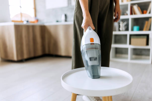 Woman with handheld vacuum cleaning small table