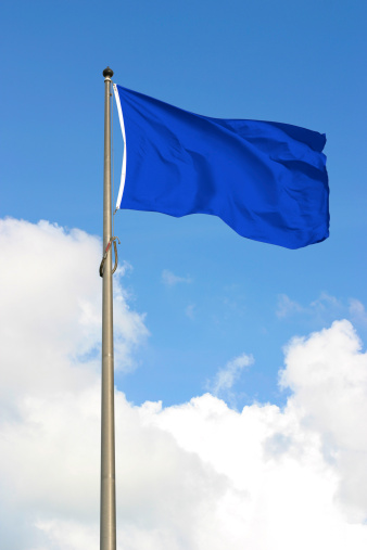 Blank blue flag, against sunny blue sky.