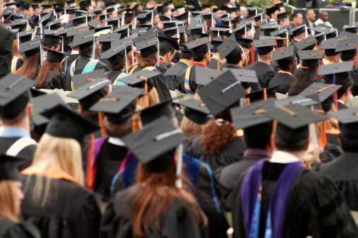 Rearview of university graduates wearing an academic gown on commencement day. Education stock photo