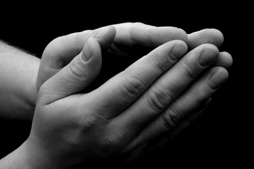 B&W hands, folded in prayer, with lighting from above.