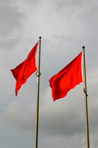 Two red flags against storm clouds.