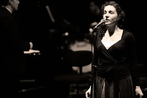 Photo of bigband: female jazz singer in performance behind the microphone
