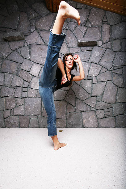 Jovem mulher dando um Karate Kick - fotografia de stock