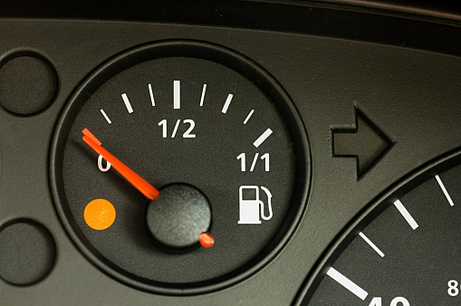 The warning light is illuminated as the petrol gauge in a car displays a low reading.