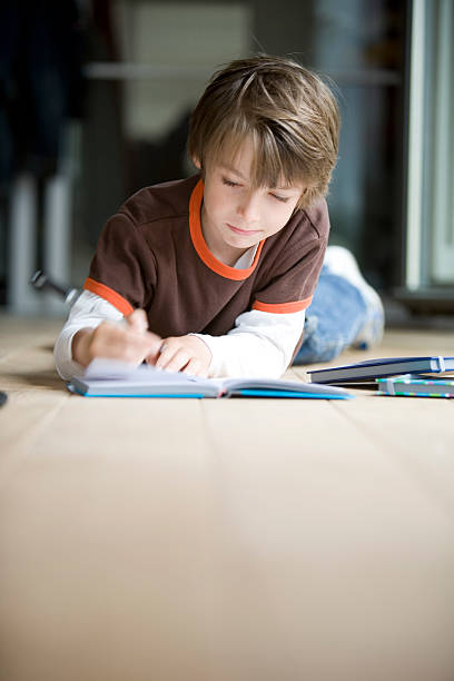 schoolboy hard at work A young boy works hard at his homework. Motion blur on the hand holding the pen. colouring stock pictures, royalty-free photos & images
