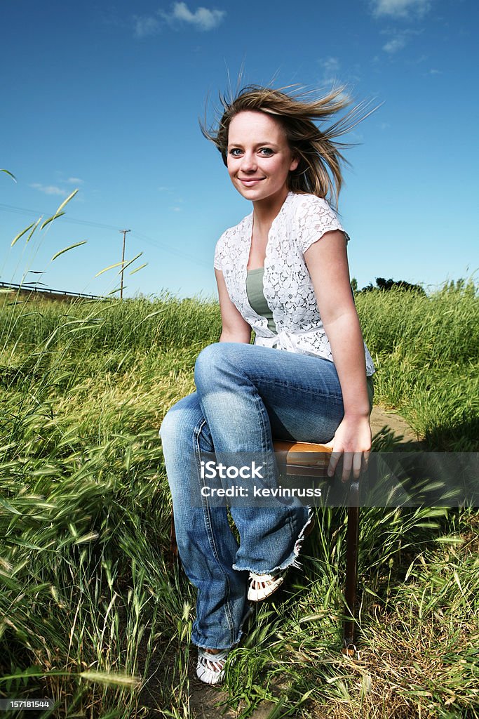 Sonriente mujer joven al aire libre en una silla - Foto de stock de A la moda libre de derechos