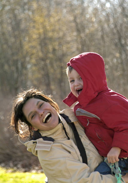 istock Laughing woman carrying  her son standing in front of trees 157181778