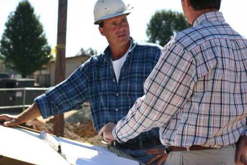 Two architects reviewing plans on site