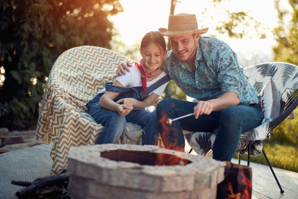 istock Father-Daughter Bonding: Cozy Marshmallow Roasting by the Fire 1571819990