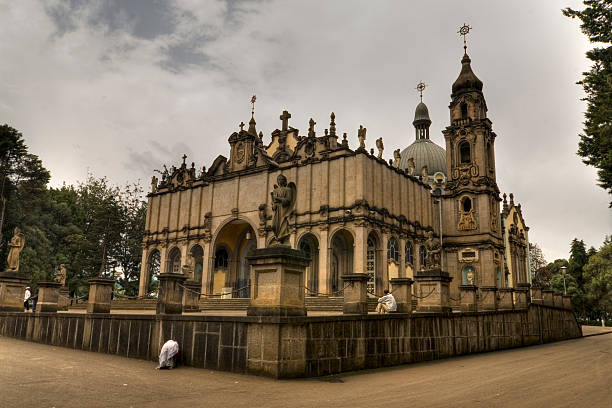 Addis Ababa Holy trinity church The holy trinity church in Addis Ababa with an orthodox priest in front of it walking towards the church. Also some people praying. Image was captured using High dynamic range digital enhancement. addis ababa ethiopia photos stock pictures, royalty-free photos & images