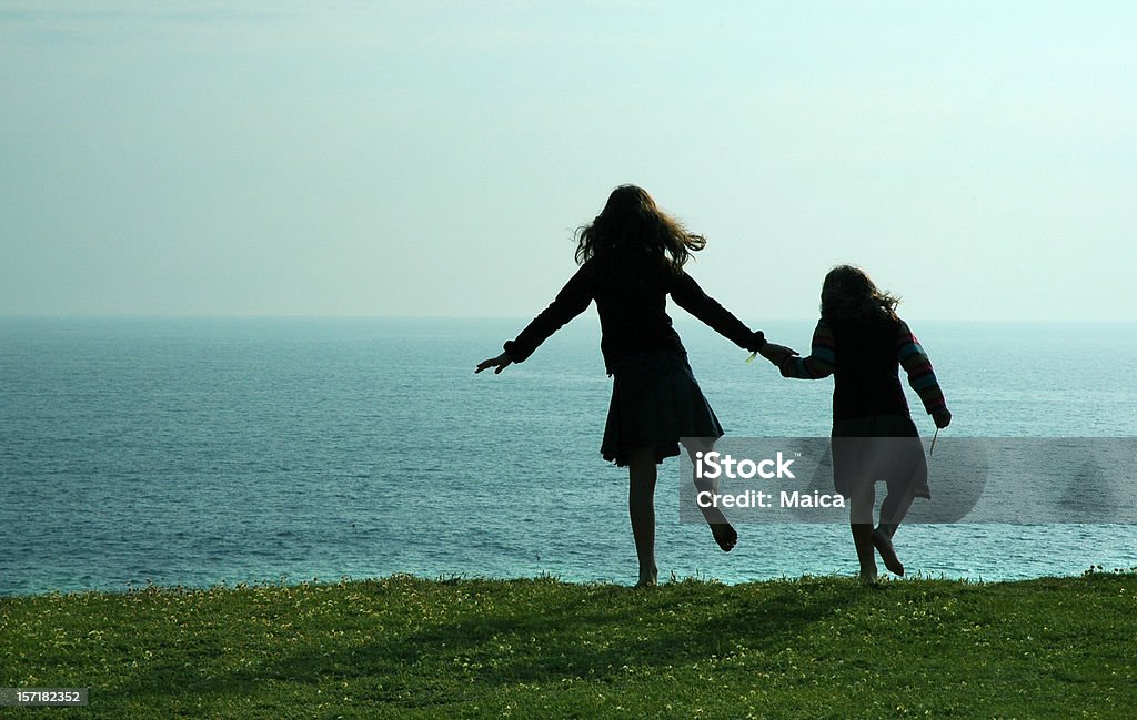 Dancing by the sea Silhouettes of two kids dancing on a cliff. 4-5 Years Stock Photo