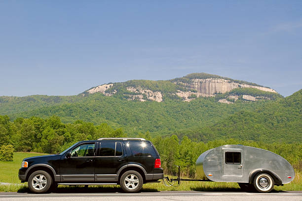 Teardrop on the Road A teardrop camper trailer behind an SUV parked on the roadside with Table Rock, SC, in the background. teardrop camper stock pictures, royalty-free photos & images