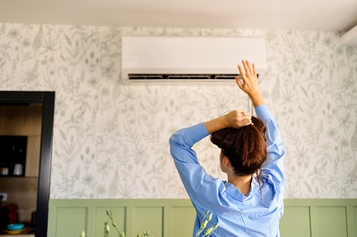 A woman checking the temperature of an Air conditioner at home