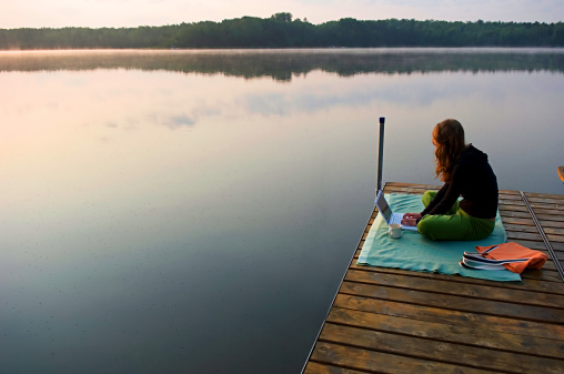 Pregnant woman doing yoga at lake at sunset.